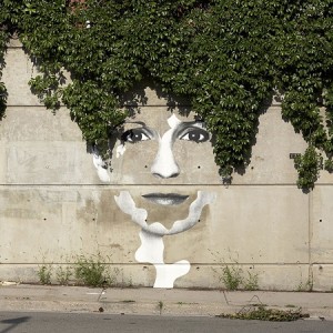 A mural of a woman 's face with ivy growing on it.