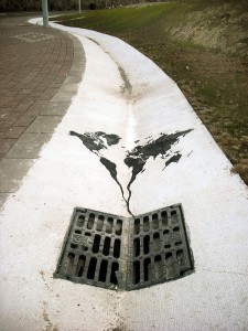 A street with a hole in the ground and a map of the world painted on it.
