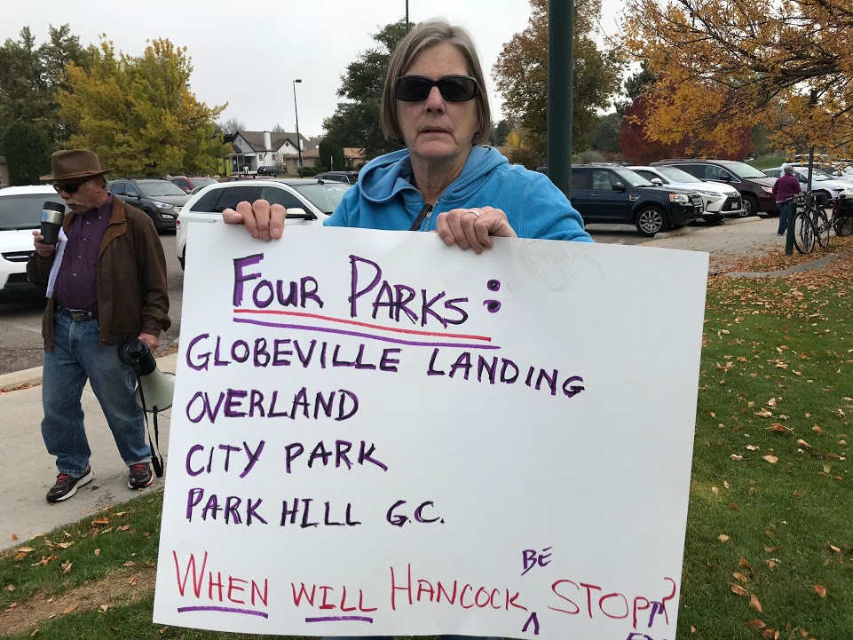 A woman holding up a sign that says four parks.