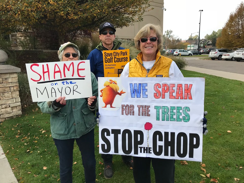 Three people holding signs in front of a building.