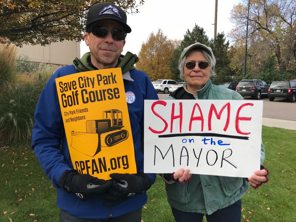 Two people holding signs in a park