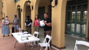 A man standing next to two women in front of tables.